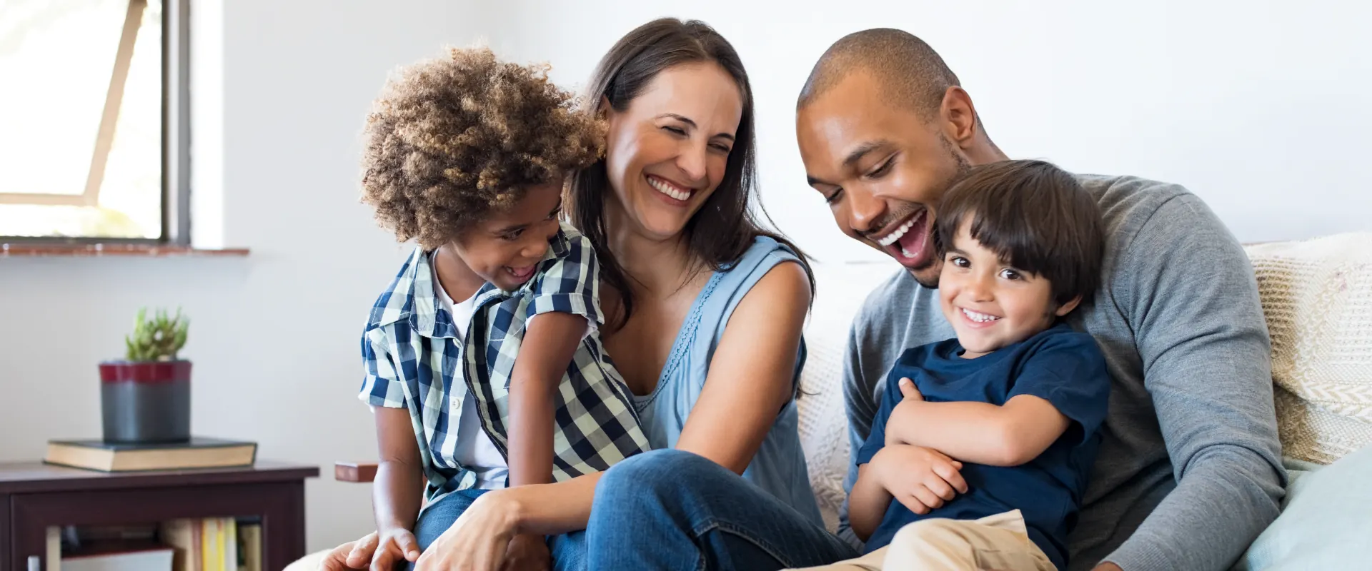 Family laughing together on a couch at home